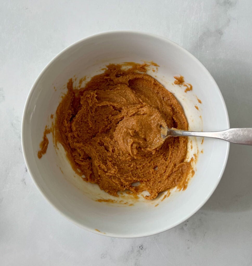 A bowl of peanut butter puree with a spoon.