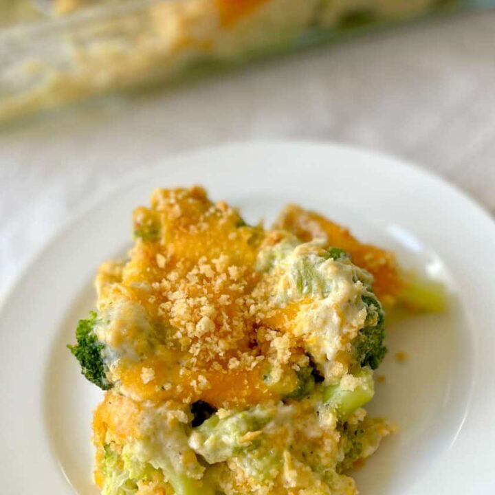 Creamy broccoli casserole with cheese and golden breadcrumb topping on white plate