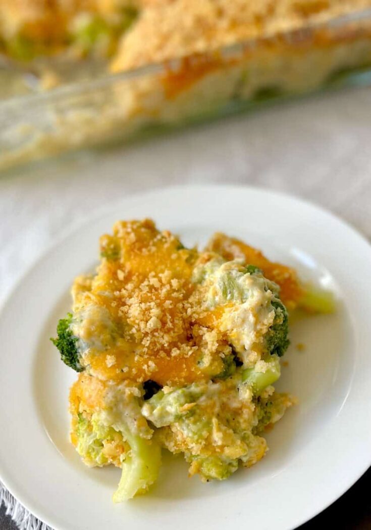 Creamy broccoli casserole with cheese and golden breadcrumb topping on white plate