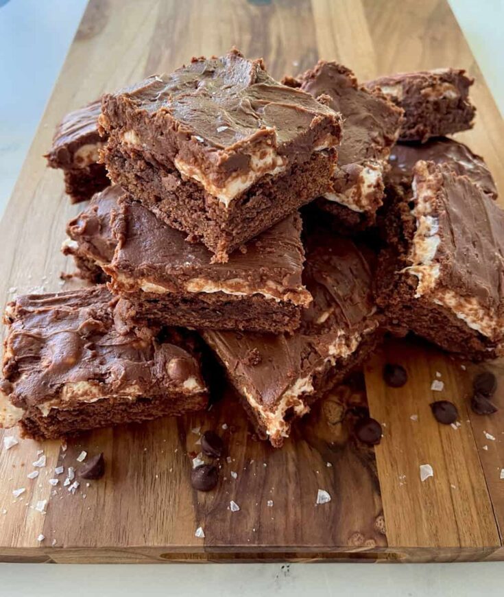 Chocolate brownies with a marshmallow filling on a wooden cutting board.