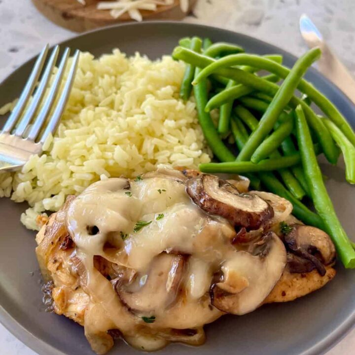 Savory chicken dish with mushrooms, rice, and green beans on a gray plate.