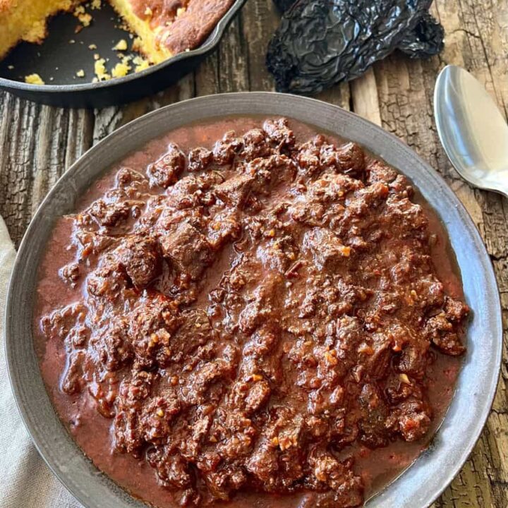 Beef chili in a rustic bowl on a wood surface.
