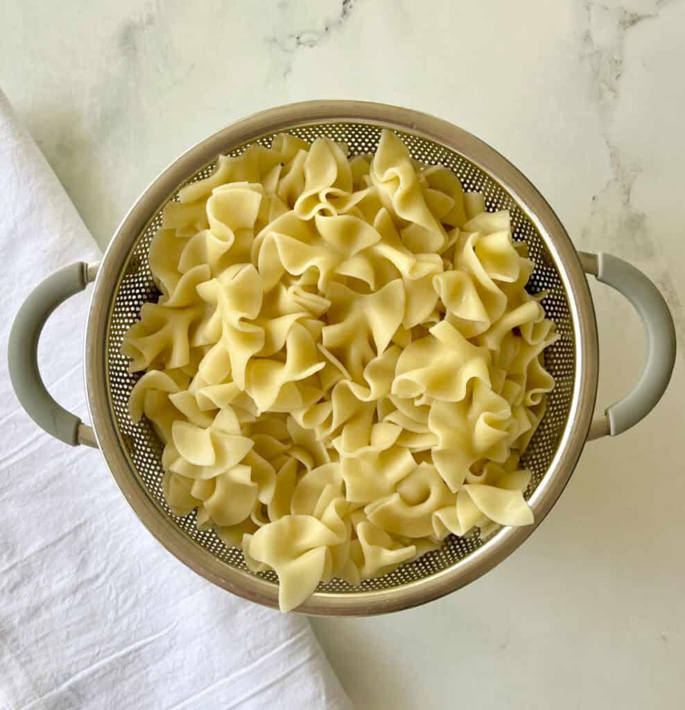 Cooked pasta in a metal colander for draining.