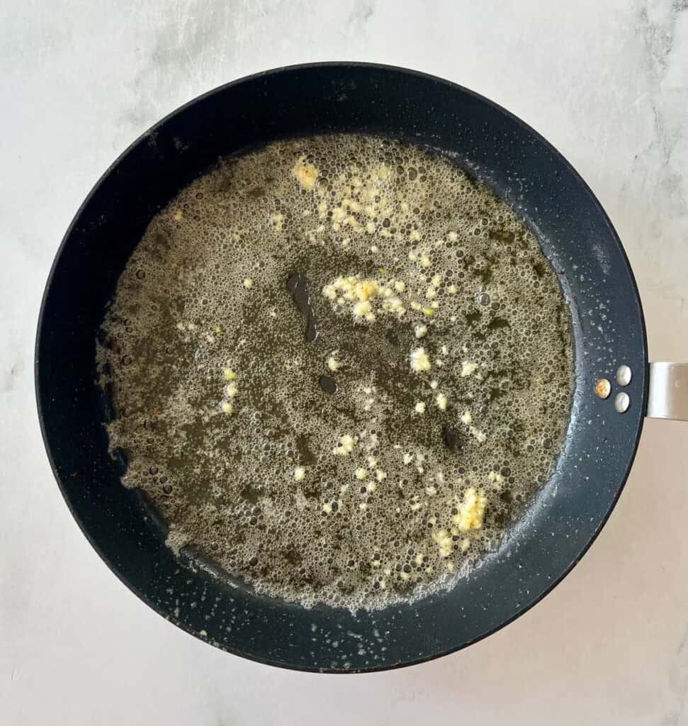 Garlic butter melting and sizzling in a frying pan.
