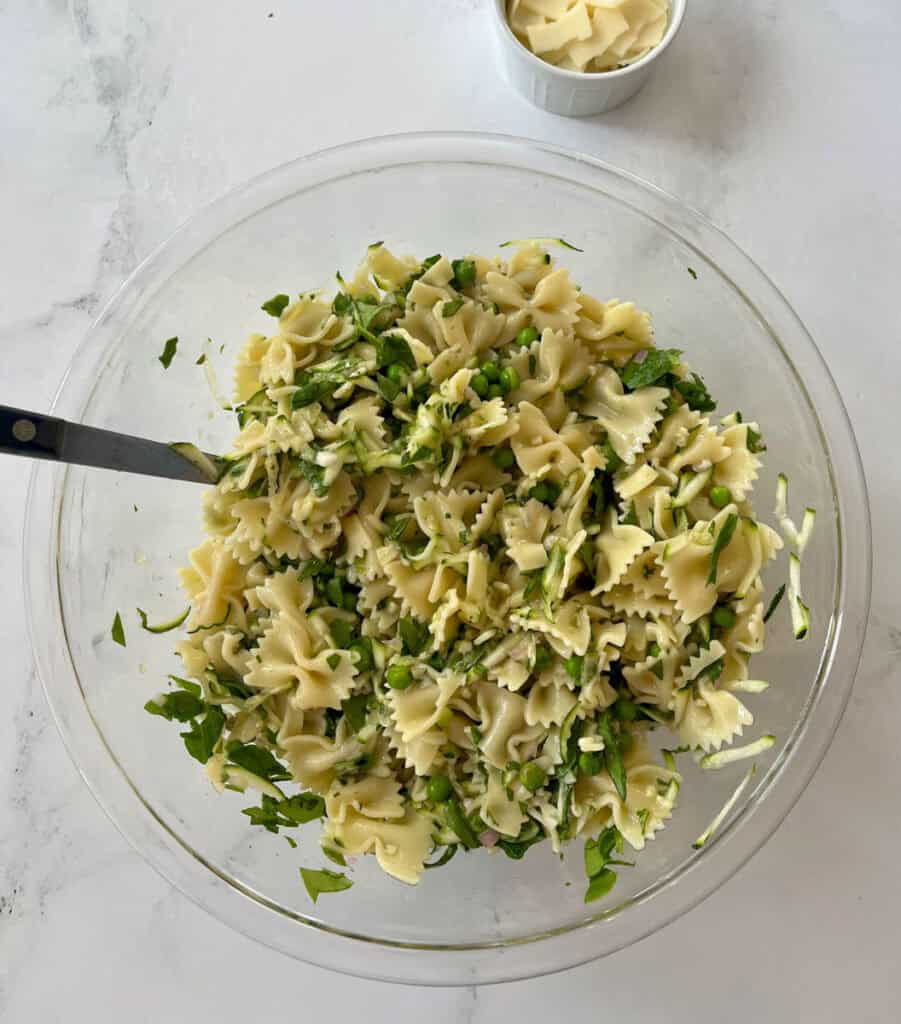 Fresh pasta salad with herbs, zucchini, spinach, and fresh basil in a glass bowl.