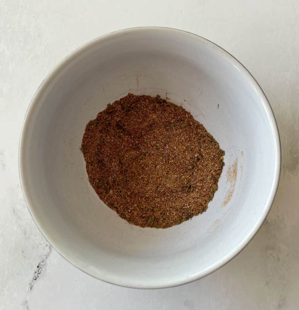 A white bowl filled with a finely ground spice blend.