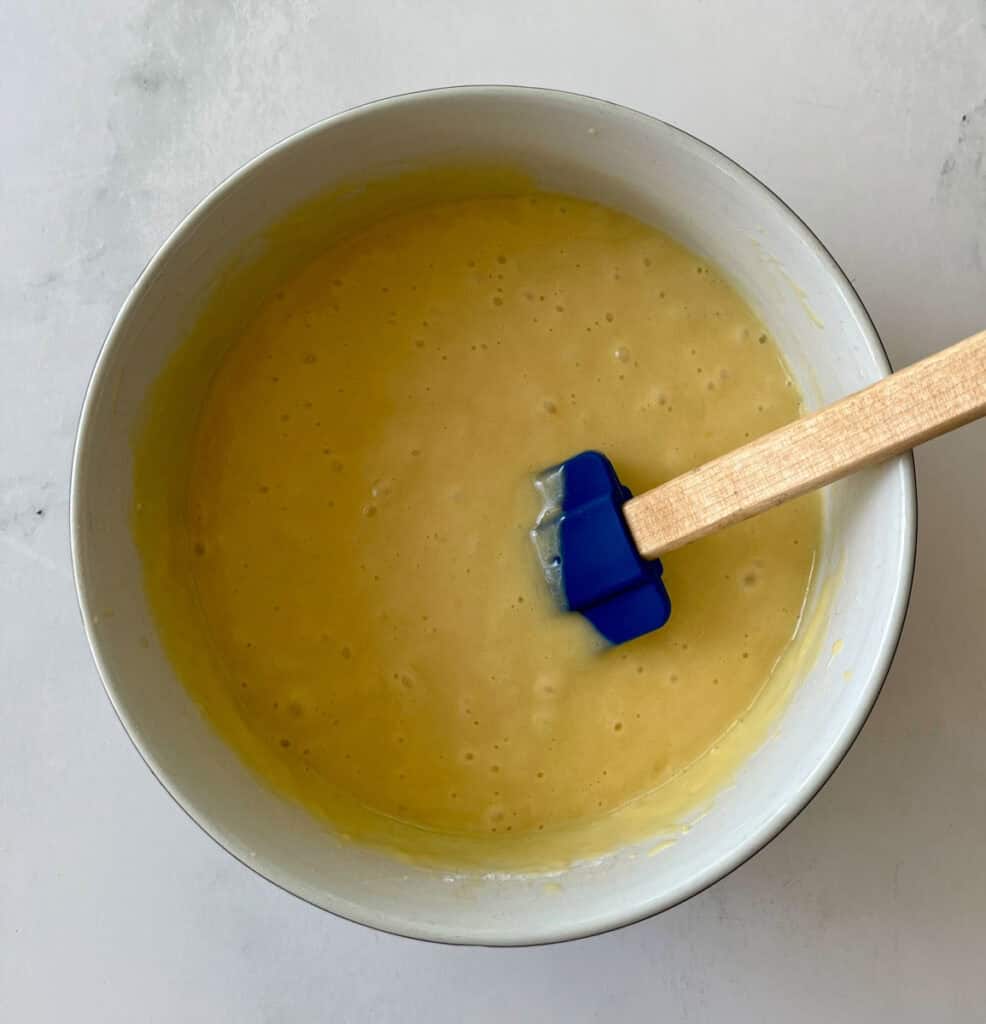 Lemon loaf batter and a rubber spatula in a white mixing bowl.
