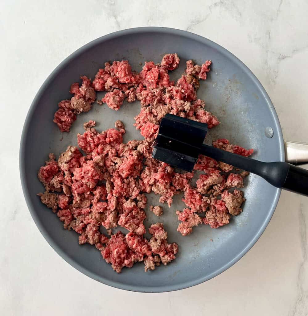 Sautéed ground beef in a skillet, on a marbled surface..