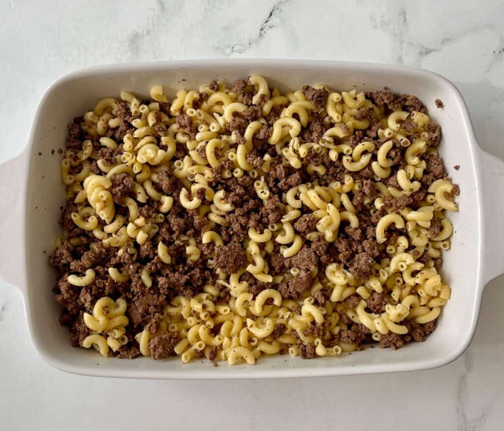Beef and macaroni casserole in a white baking dish, ready to bake.
