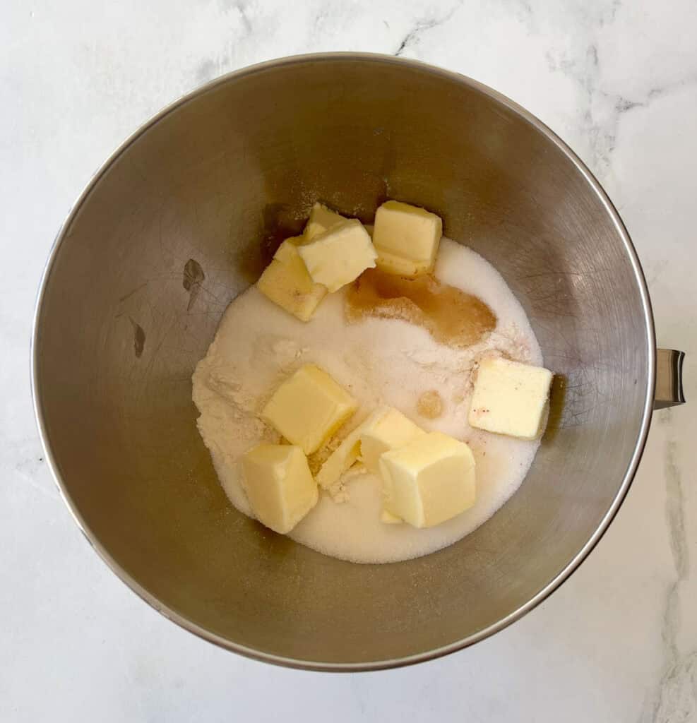 A close-up of butter, sugar, and vanilla extract in a mixing bowl.