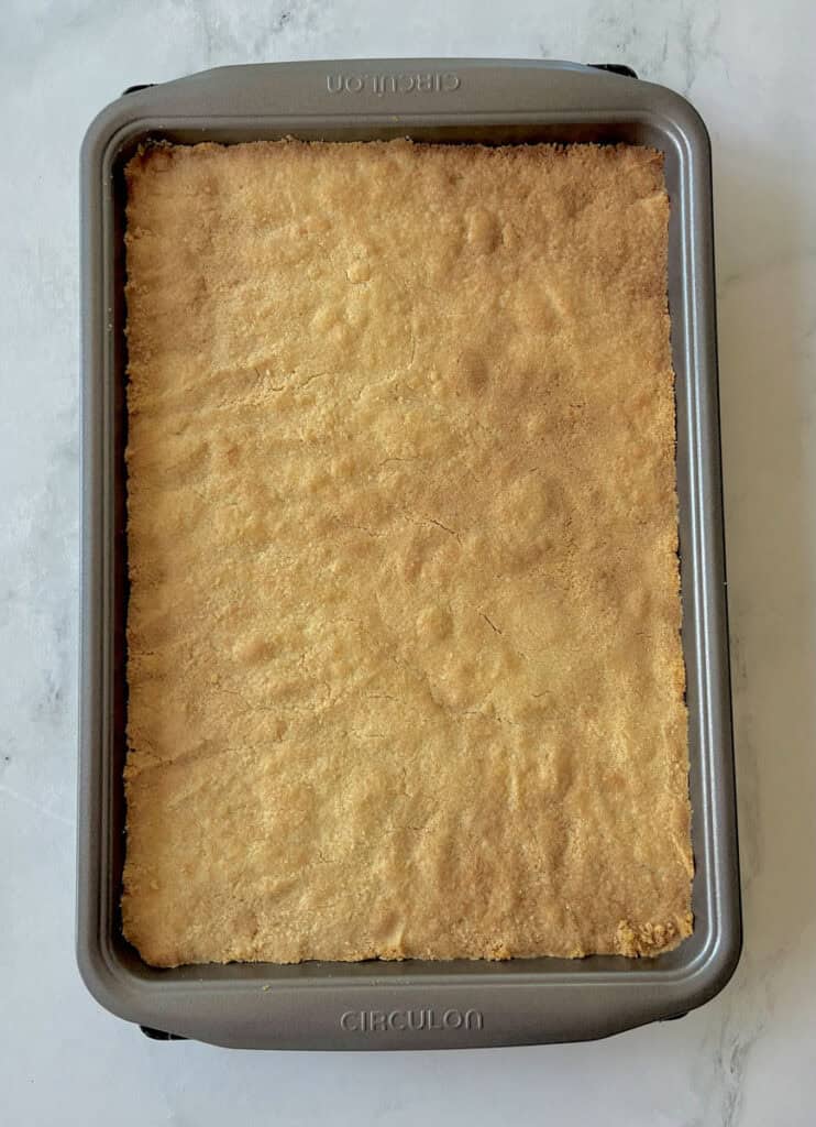 A rectangular baking pan with a baked crust in it on a white surface.
