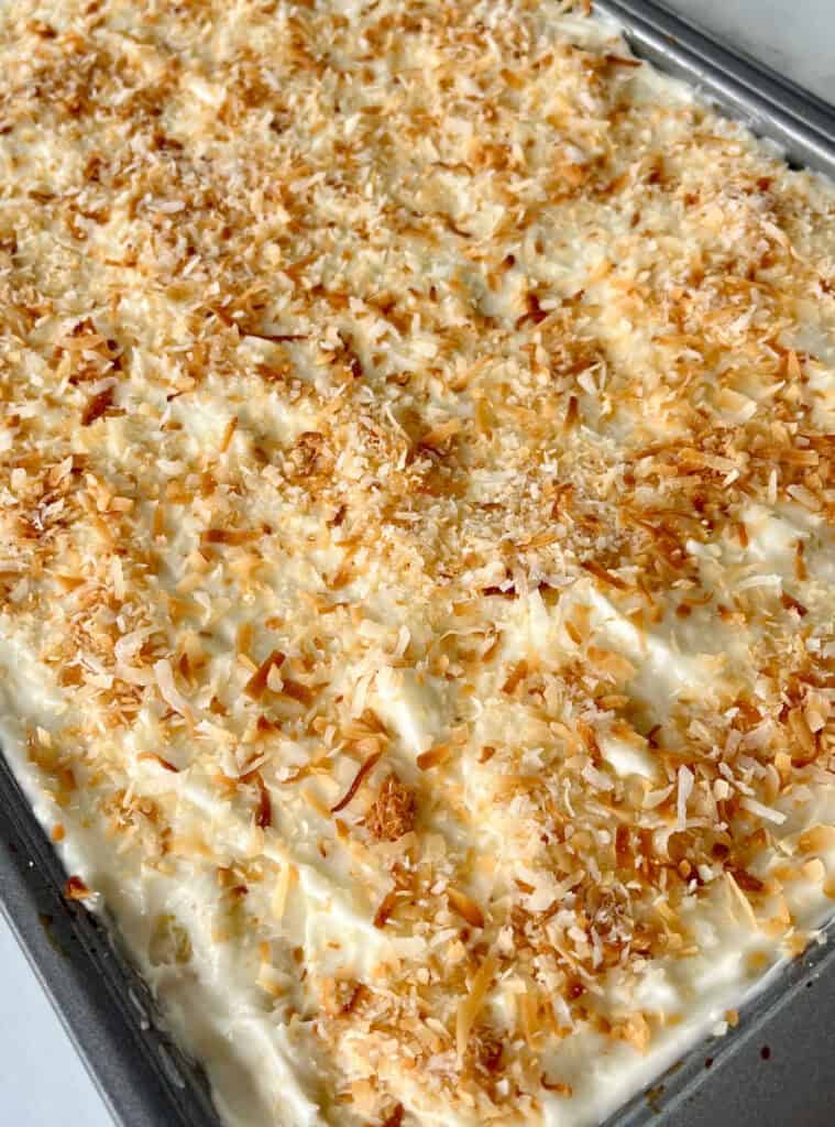 Close-up of pineapple bars with toasted coconut topping in a baking dish.