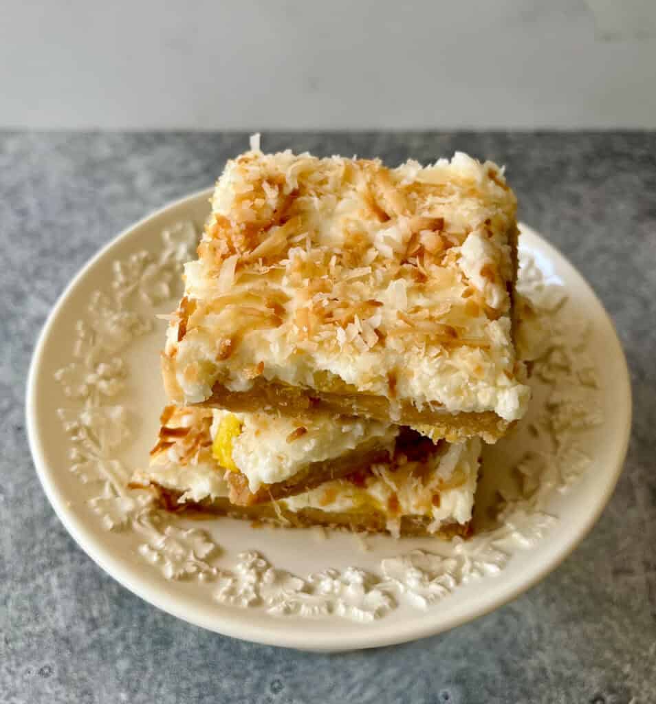 Close-up image of pineapple bars with toasted coconut topping on a white plate.
