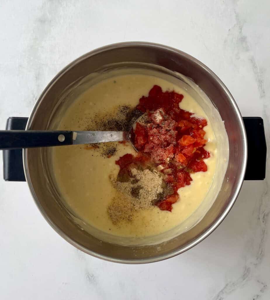 Cooking creamy sauce with tomatoes and spices in a pot.