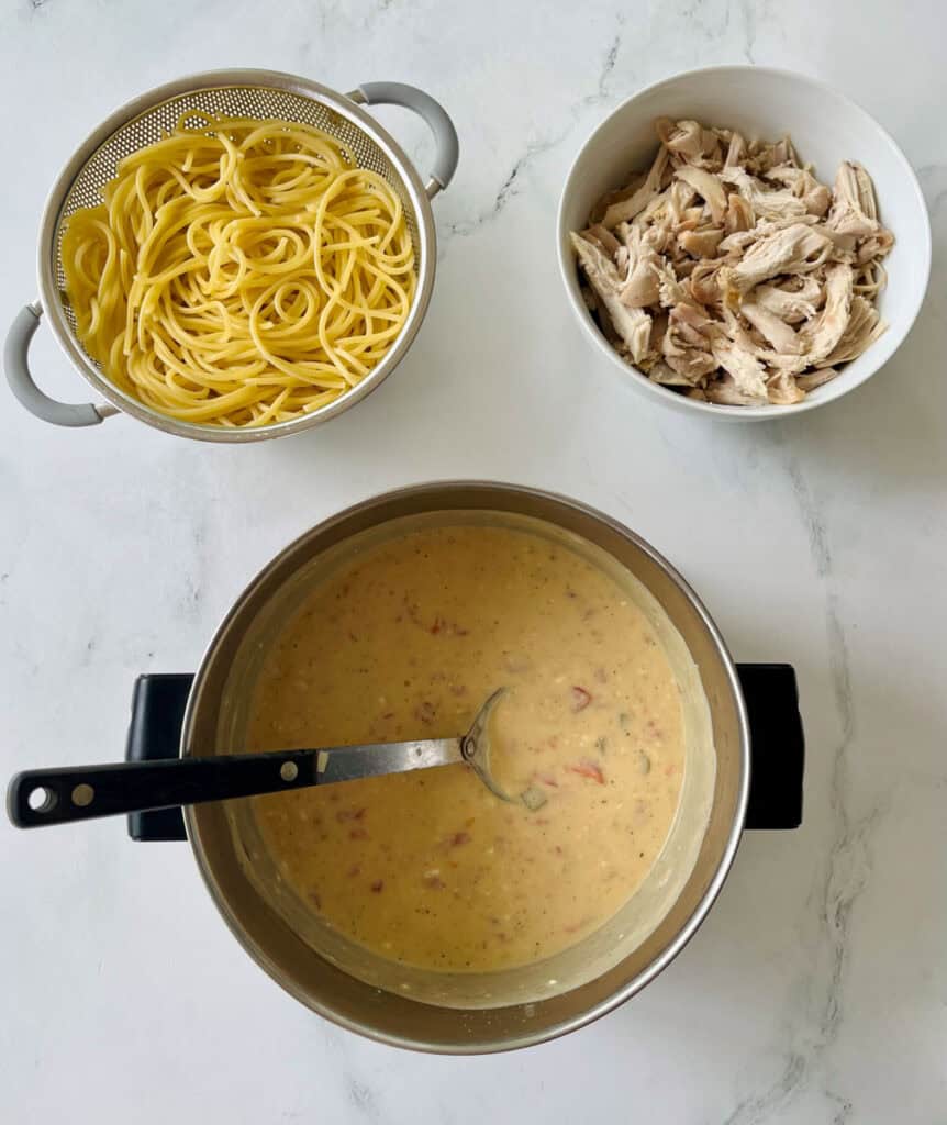 Creamy chicken pasta sauce with shredded chicken and cooked spaghetti.