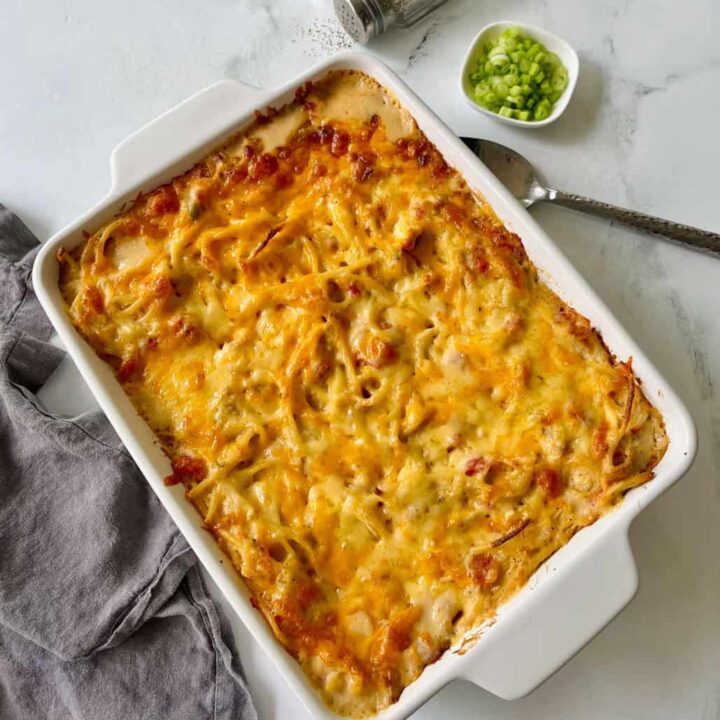 Delicious baked cheesy chicken spaghetti casserole in a white baking dish.