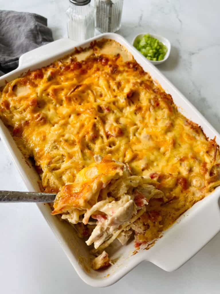Baked cheesy chicken spaghetti casserole in a white dish.