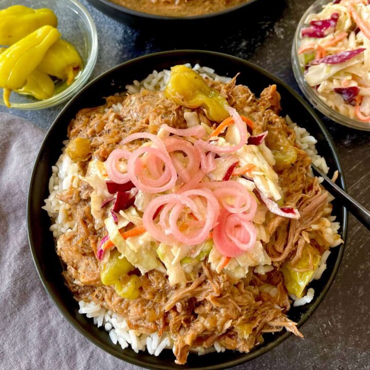 Pulled pork rice bowl topped with pickled onions and coleslaw. With side dishes of peppers and coleslaw.