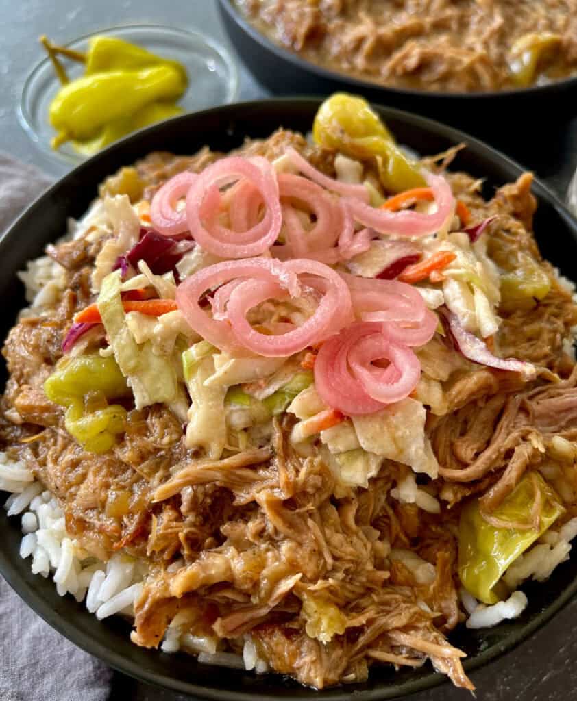 Savory pulled pork rice bowl topped with pickled onions and coleslaw.