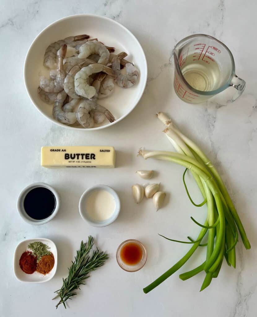 Raw shrimp, green onions, garlic, butter, and seasonings for BBQ shrimp.