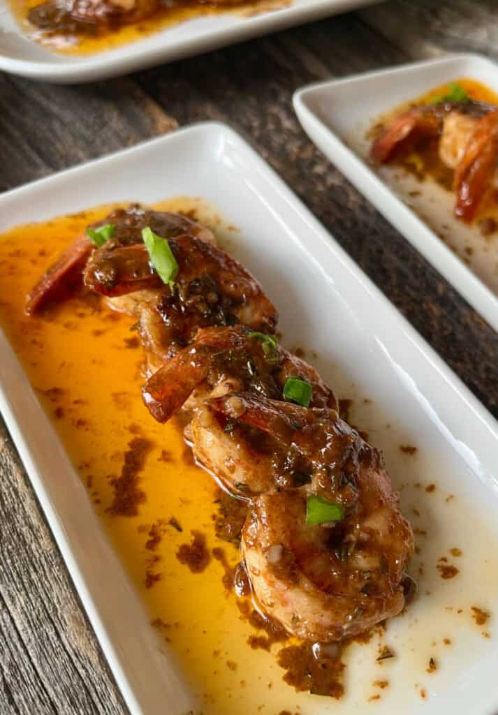 Sautéed shrimp with sauce and green onions on white plate.