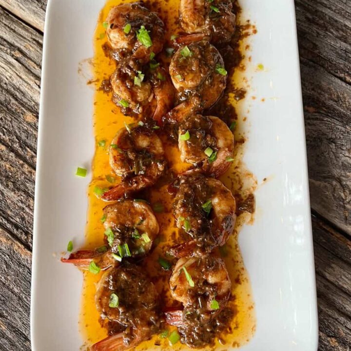 Delicious shrimp with savory sauce and herbs on a white plate.