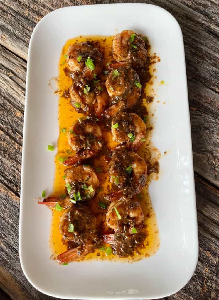 Delicious shrimp with savory sauce and herbs on a white plate.
