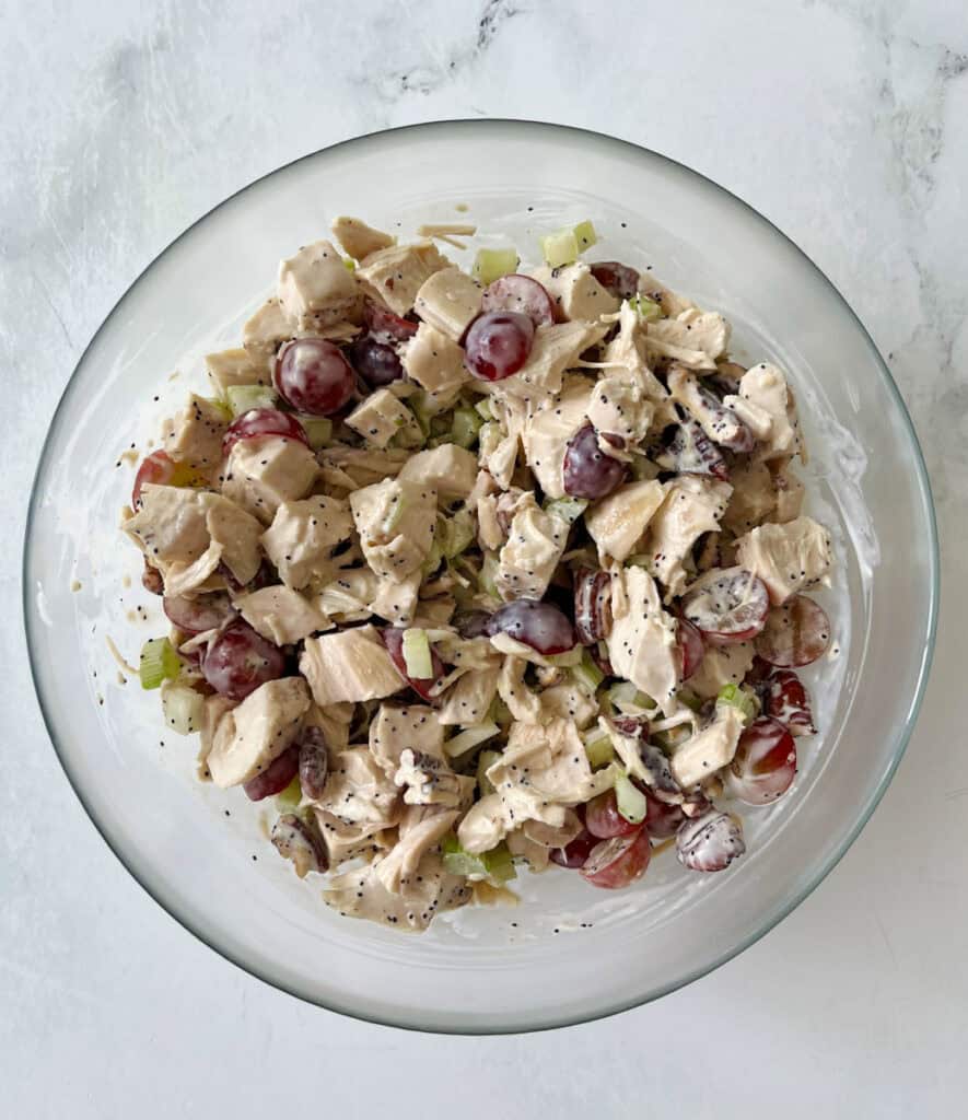 Fresh chicken salad with grapes, celery, and herbs in a glass bowl.