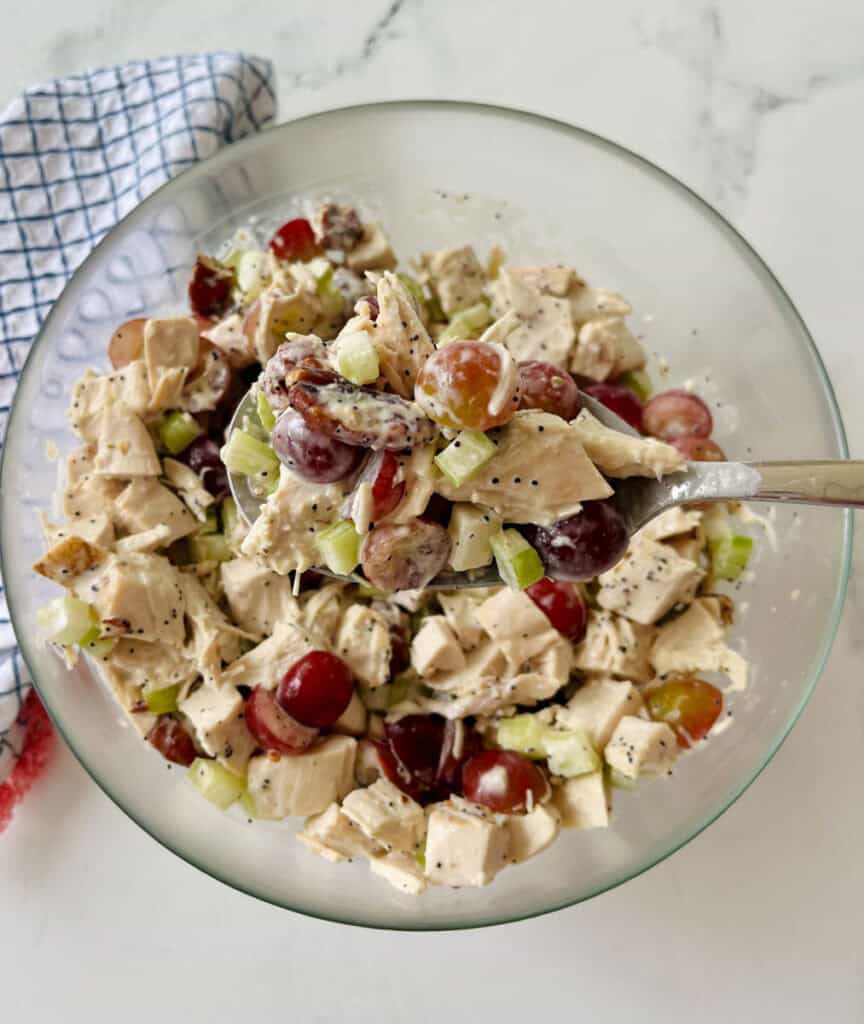 Fresh chicken salad with grapes, celery, and herbs in a glass bowl.