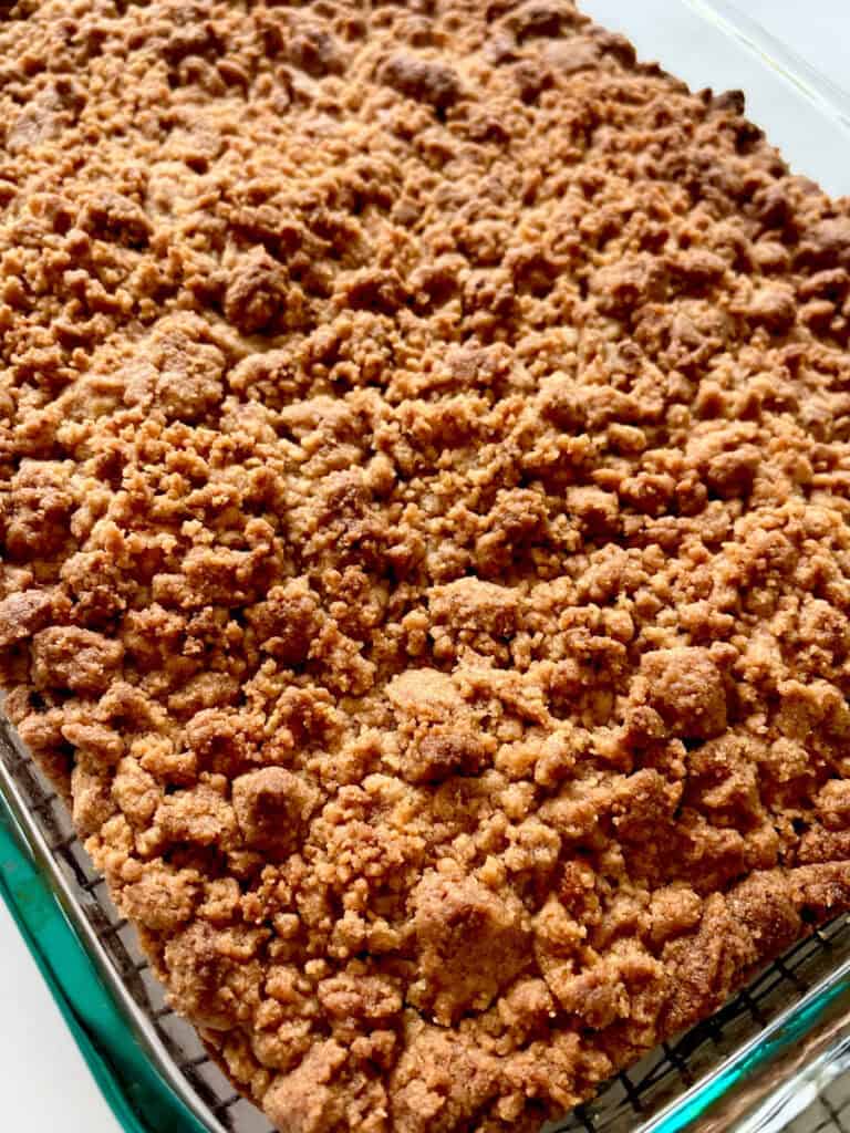 Close-up of a baked coffee cake with a crumbly cinnamon topping in a glass dish.