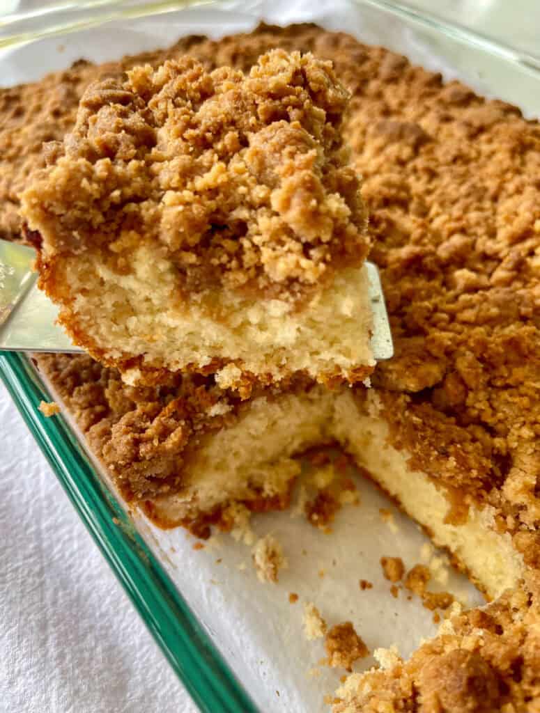 Close-up of crumb-topped cake slice in a glass dish.