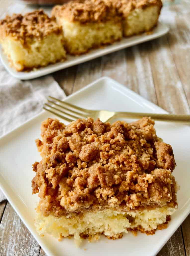 Close-up of a coffee cake slice with crumb topping on a white plate.