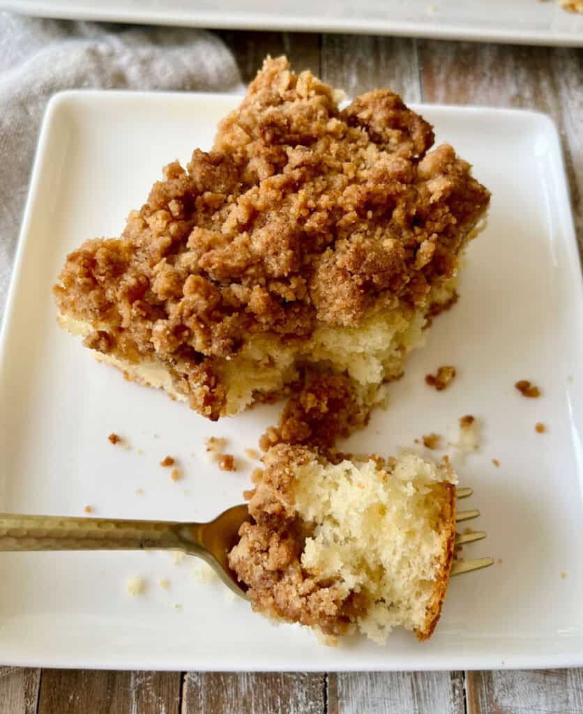 Close-up of a slice of cinnamon streusel coffee cake on a white plate.