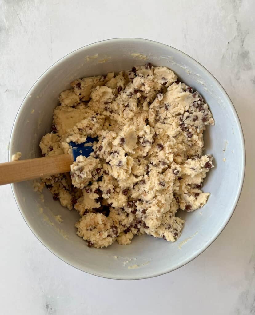 Shortbread cookie dough with chocolate chips and toffee bits in a mixing bowl for baking.