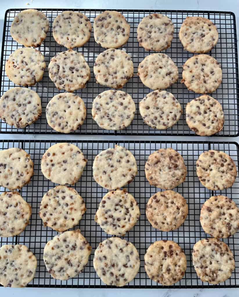 Freshly baked shortbread cookies with chocolate chips and toffee bits cooling on wire racks.