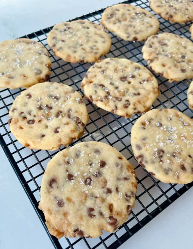 Freshly baked shortbread cookies with chocolate chips and toffee bits cooling on a wire rack.