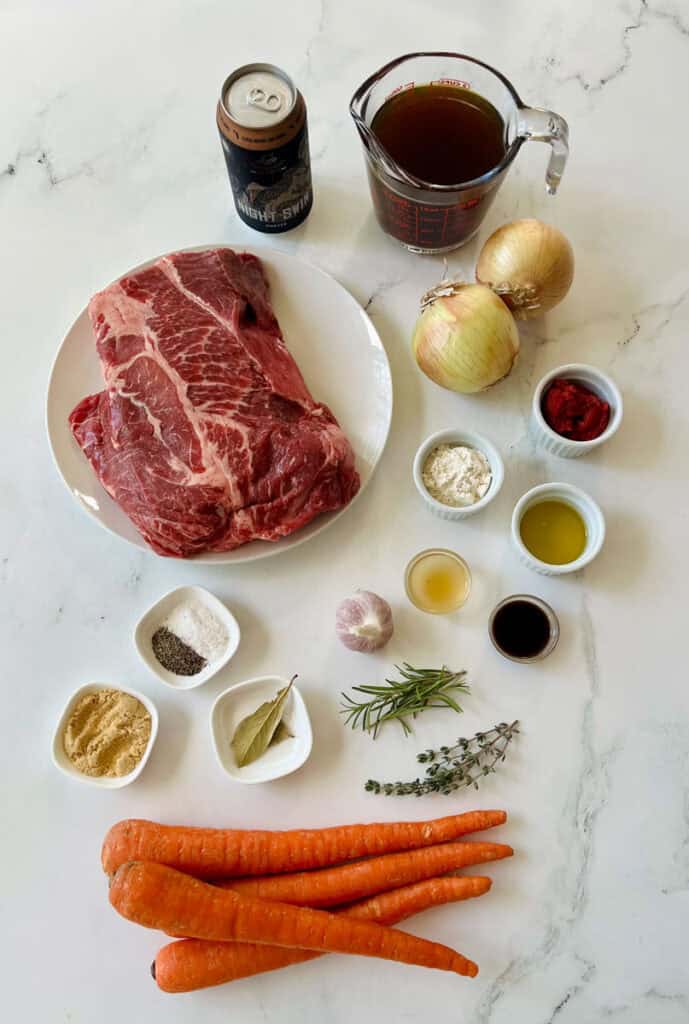 Raw beef, vegetables, and seasonings for pot roast preparation.