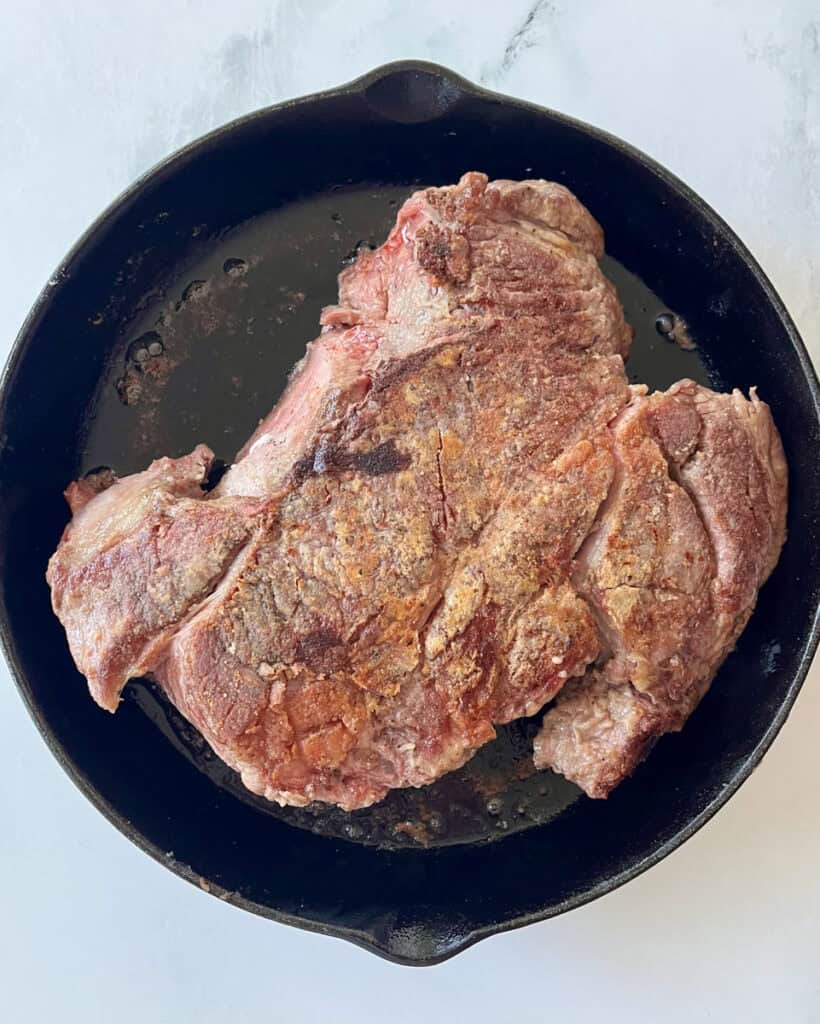 Browned beef roast in a black cast iron skillet ready for cooking.