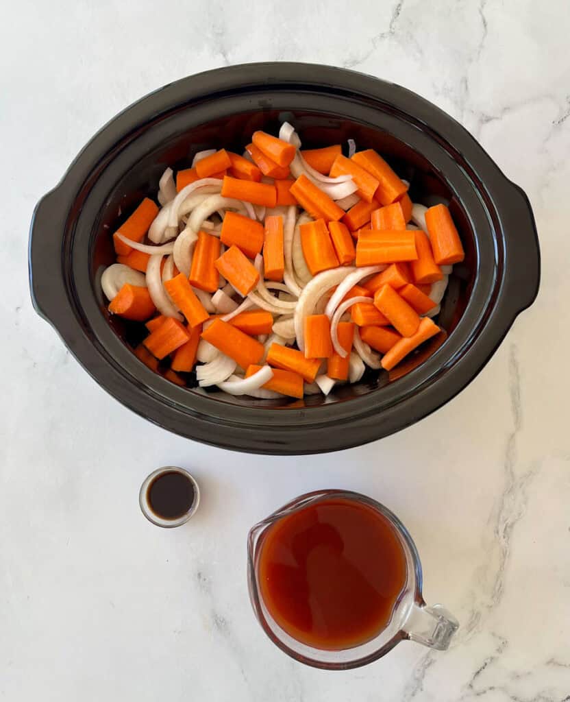 Chopped carrots and onions in slow cooker with broth and Worcestershire sauce.
