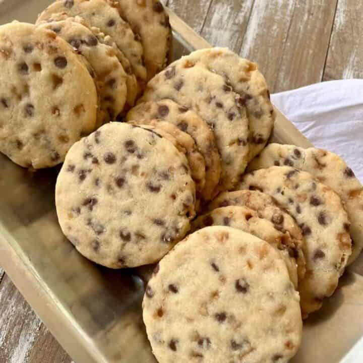 Freshly baked shortbread cookies with chocolate chips and toffee bits on a tray.