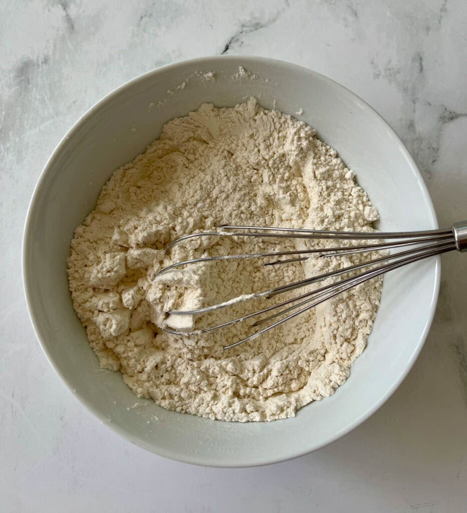 Bowl of a flour mixture with a whisk for baking or cooking.