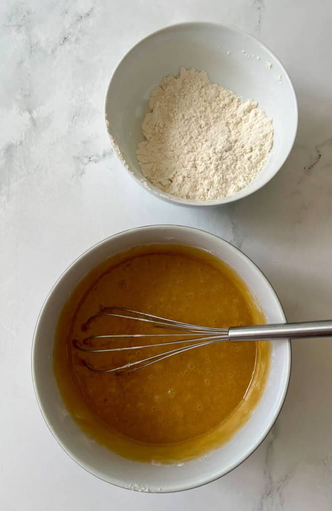 Flour and liquid mixture for baking in white bowls.