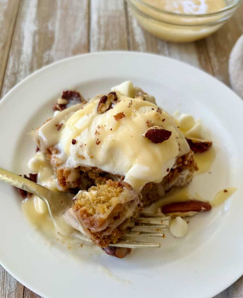 Close-up of cookie dough dessert bars with vanilla ice cream, white chocolate and nuts on a white plate.