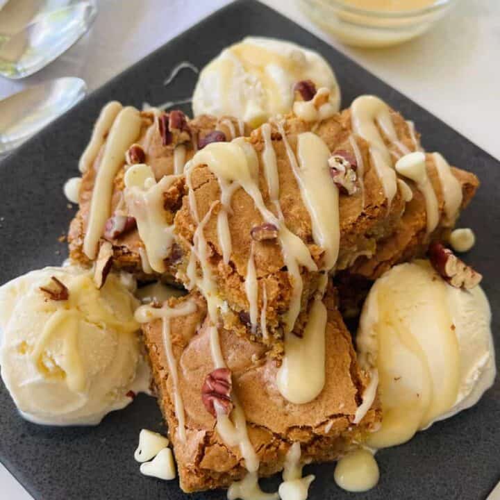 Close-up of cookie dough dessert bars with vanilla ice cream, white chocolate and nuts.