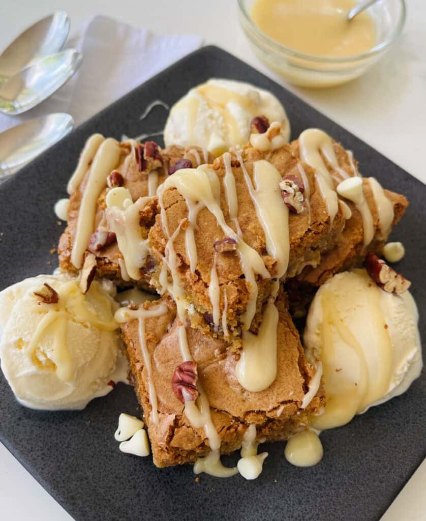 Close-up of cookie dough dessert bars with vanilla ice cream, white chocolate and nuts.