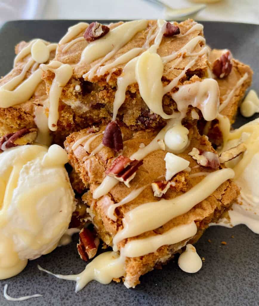 Close-up of cookie dough dessert bars with vanilla ice cream, white chocolate and nuts.