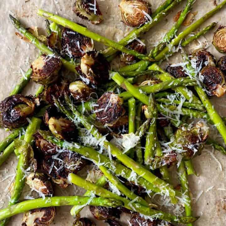 Roasted asparagus and Brussels sprouts with grated cheese and lemon wedge.
