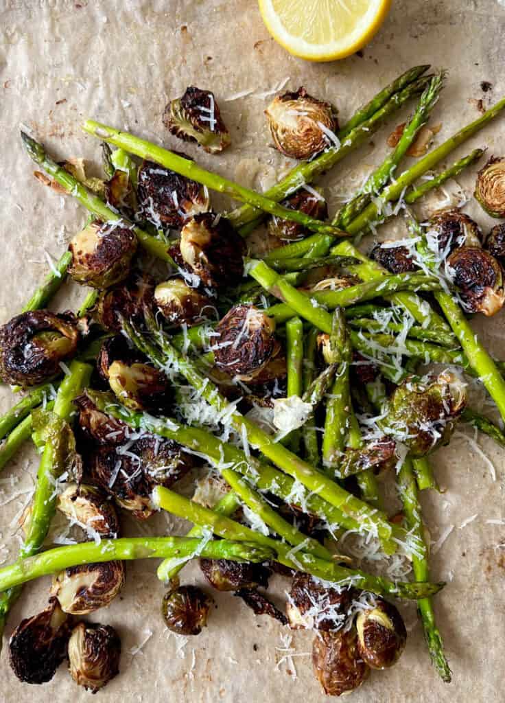 Roasted asparagus and Brussels sprouts with grated cheese and lemon wedge.