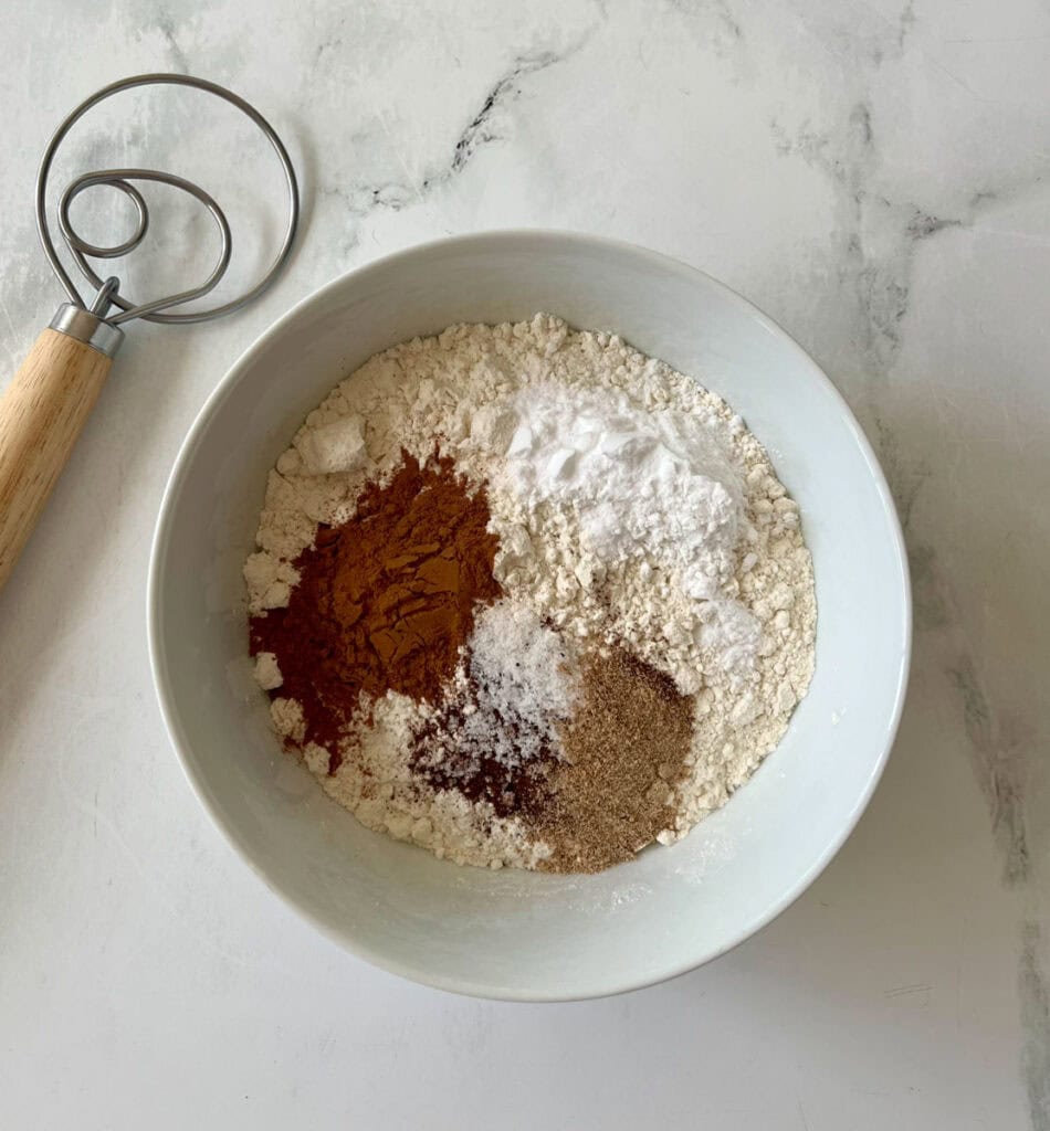 Mixing bowl with flour, ground cinnamon, and spices for baking cookies.