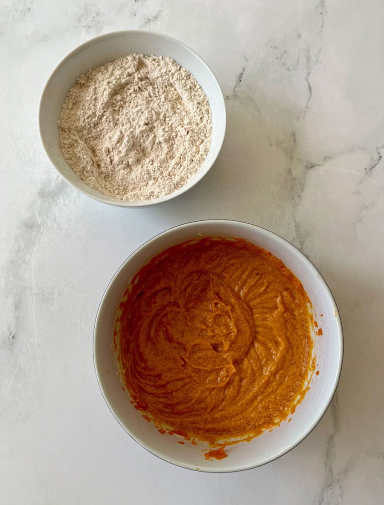 Bowl of flour and bowl of pumpkin puree mixture for baking.
